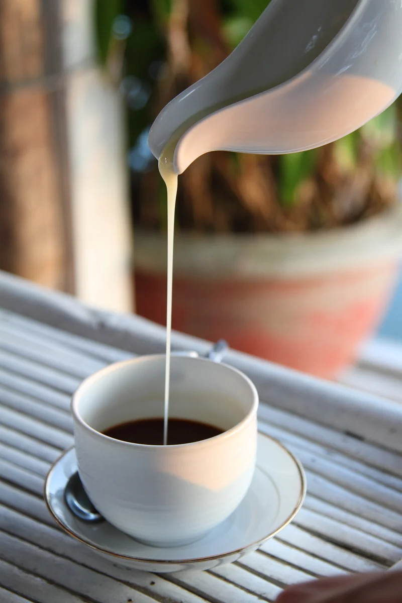 Condensed milk being poured into Vietnamese-style filter coffee